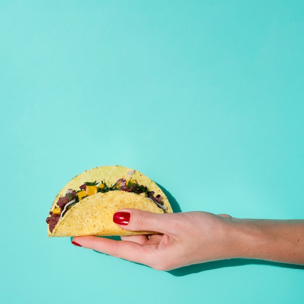 Free photo close-up woman holding taco with green background and copy-space