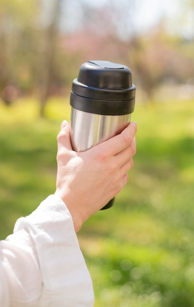 Free photo close-up woman holding thermos in nature