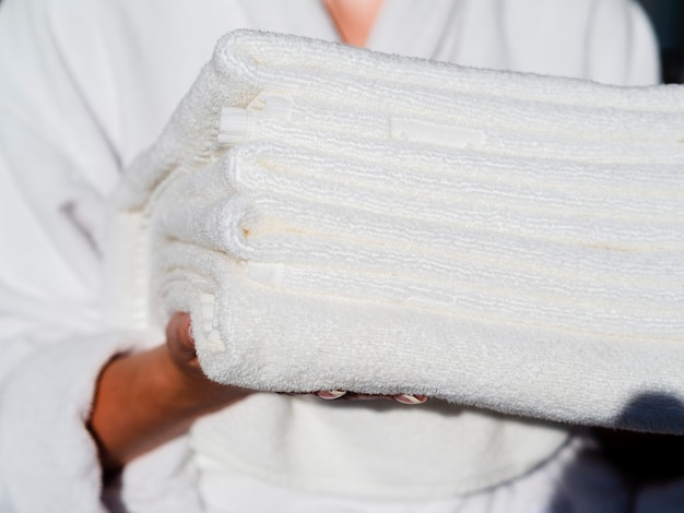 Free photo close-up woman holding white folded clean towels