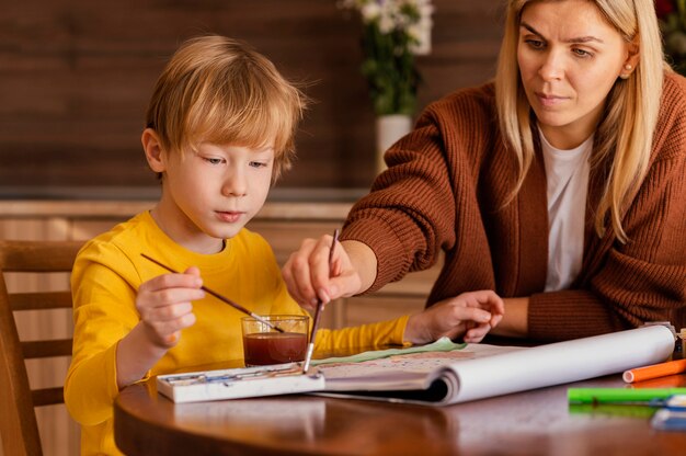 Close-up woman and kid using watercolors