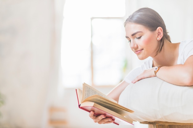 Close-up of woman lying on bed reading book