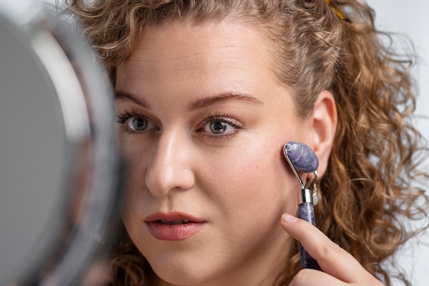 Close up woman massaging face with gua sha tool