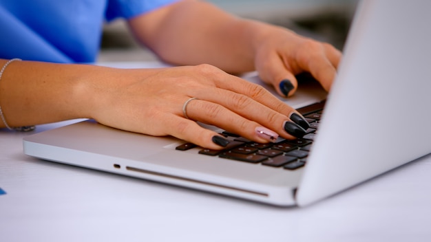 Free photo close up of woman nurse typing patient health report on laptop keyboard making appointments in medical clinic, patient registration. healthcare physician in medicine uniform writing treatments.