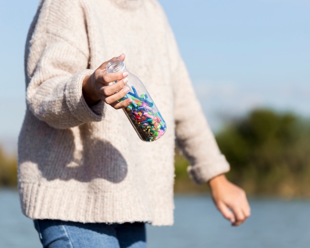 Close-up woman picking plastic from seaside