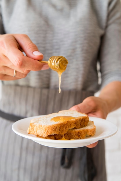 Free Photo close-up woman pouring honey ober bread slice