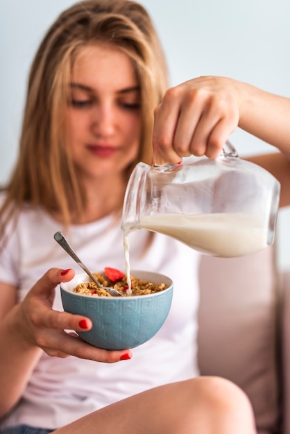 Close-up woman pouring milk in bowl