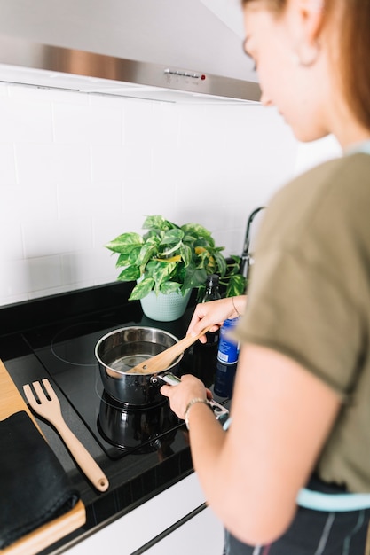 Free Photo close-up of woman preparing food in saucepan over electric stove in kitchen