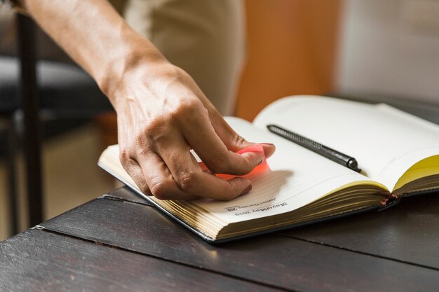 Close-up woman putting sticky note on notebook