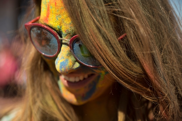 Free photo close-up of woman's face covered with holi color wearing eyeglasses