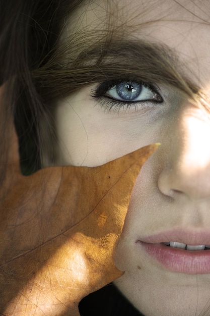 Free photo close-up of a woman's face with a dry leaf