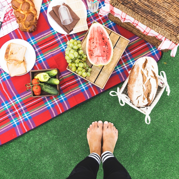 Free photo close-up of woman's feet near the picnic snack on blanket