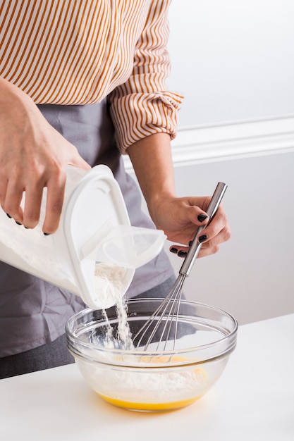 Free Photo close-up of a woman's hand adding the flour in the bowl