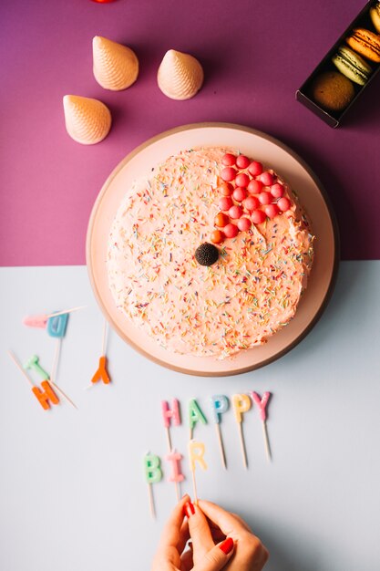 Close-up of a woman's hand arranging birthday candles on dual background