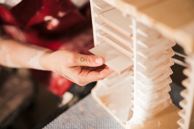 Free photo close-up of a woman's hand arranging the painted tiles in the rack