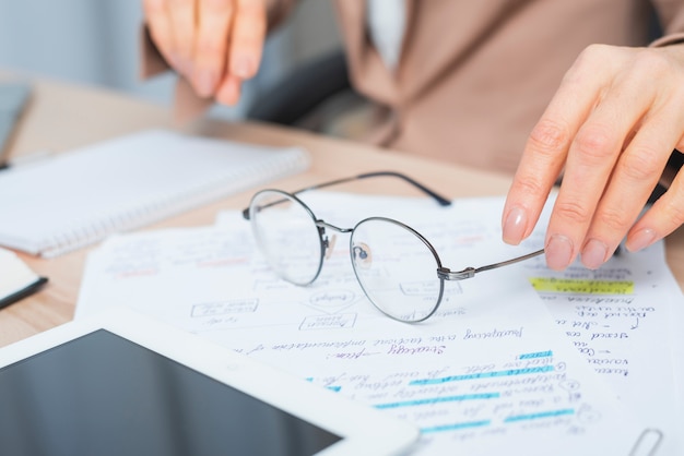 Close-up of woman's hand holding eyeglasses over the document