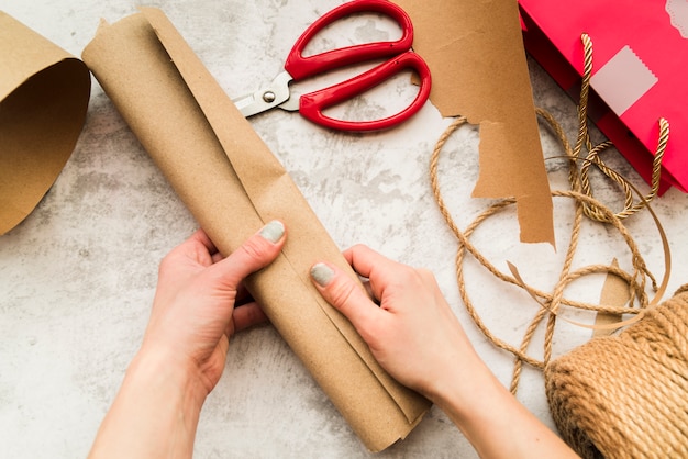 Free photo close-up of woman's hand holding rolled up brown paper