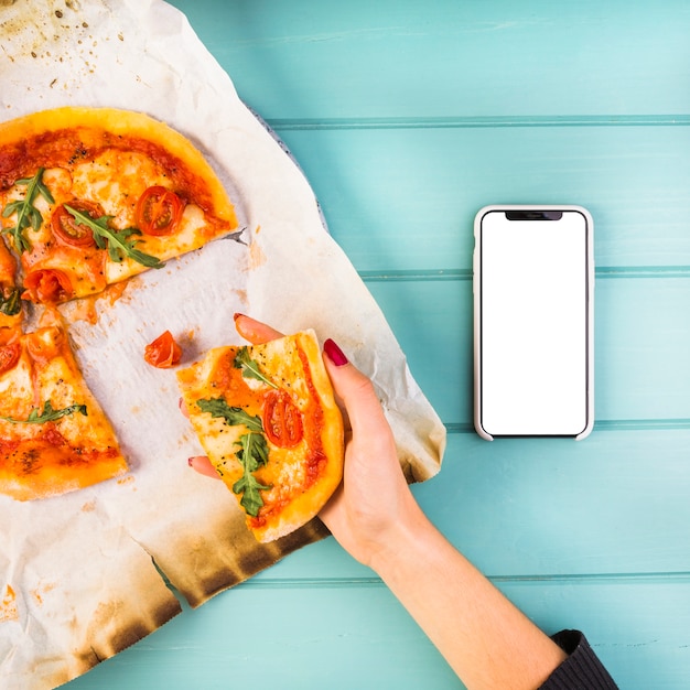 Free photo close-up of woman's hand holding slice of pizza