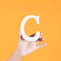 Free photo close-up of a woman's hand holding the white capital alphabet c