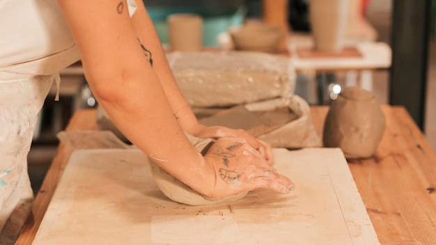 Free Photo close-up of woman's hand kneading clay on the board