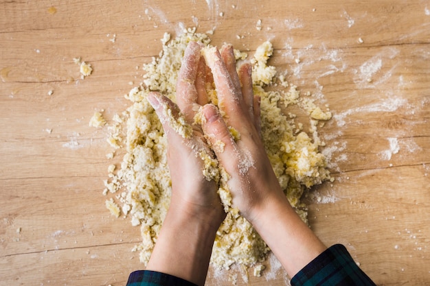 Close-up of a woman's hand kneading the dough for preparing italian gnocchi on wooden desk