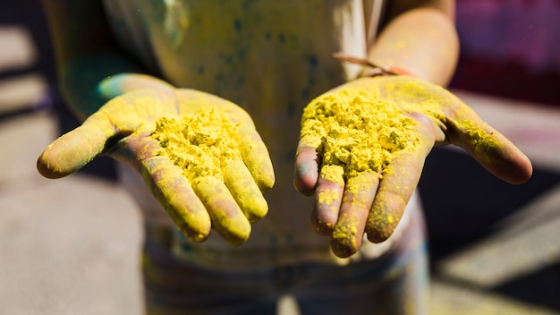 Free photo close-up of woman's hand showing yellow holi color