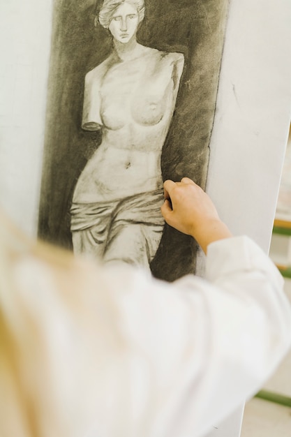 Close-up of woman's hand sketching sculpture on canvas