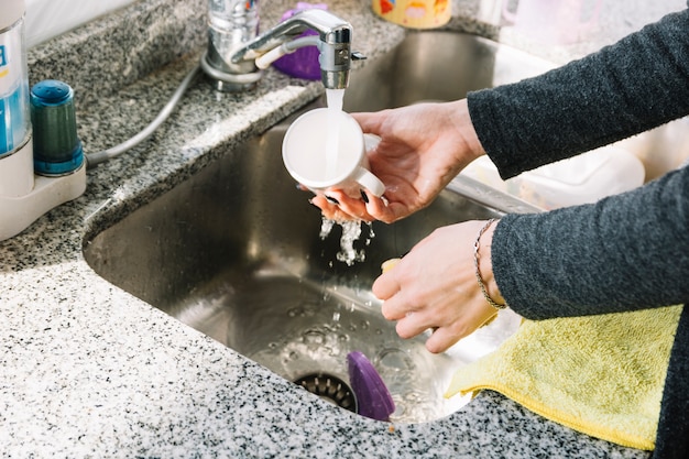 Free photo close-up of a woman's hand washing cup in kitchen sink