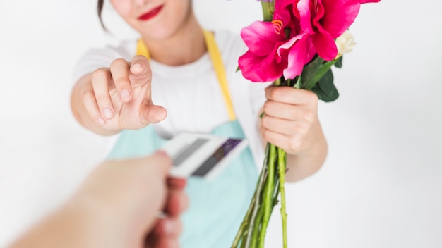 Free photo close-up of a woman's hand with flowers taking credit card from her customer