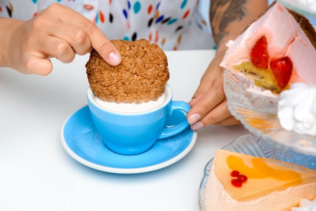 Close up of woman's hands dipping cookie in milk