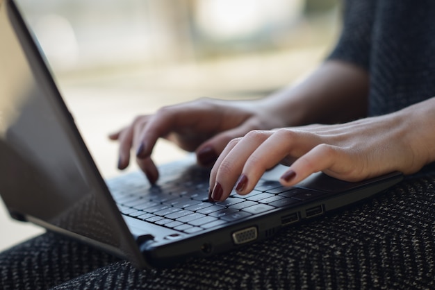 Free Photo close-up of woman's hands with painted nails typing on laptop