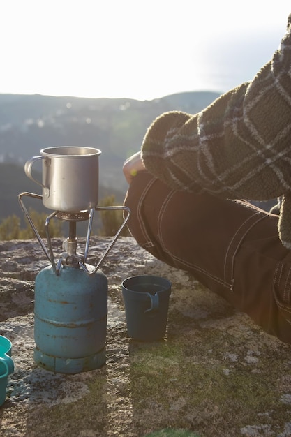 Free photo close-up of woman sitting at mug on portable camp stove