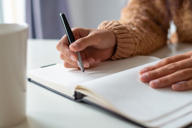 Close-up of woman sitting at table and planning schedule