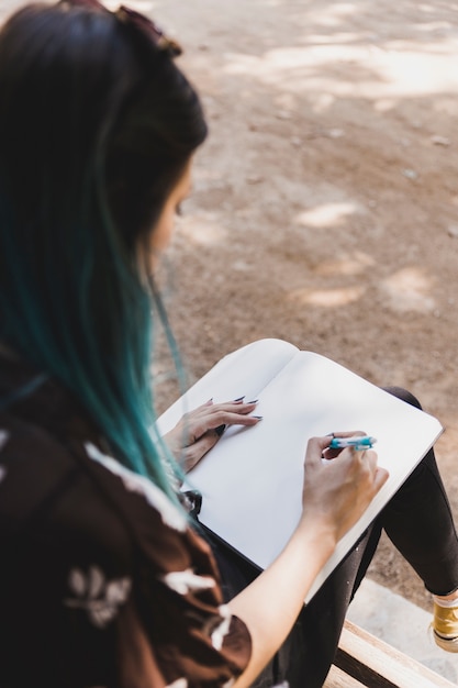 Close-up of a woman sketching on notebook with pen