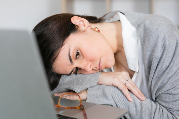 Close-up woman sleepig on glass table near laptop