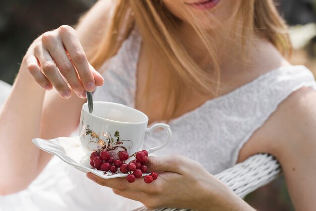 Close-up of woman stirring coffee with spoon in the ceramic cup