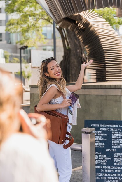 Close-up of woman taking photograph of her female friend posing at outside