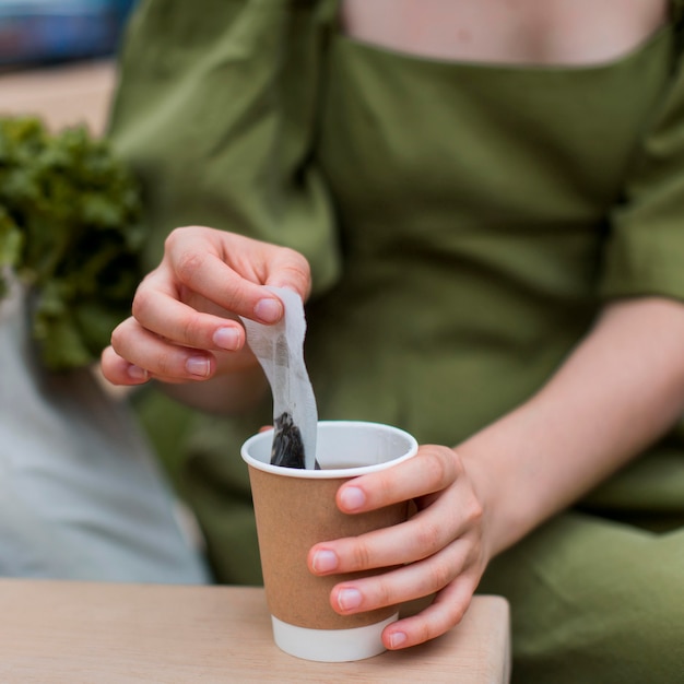 Close-up woman taking tea bag out of cup