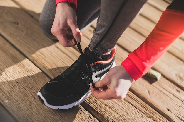 Free photo close-up of woman tying her shoelaces on wooden floor