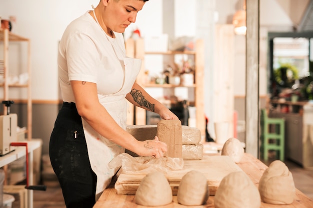 Close-up of woman unwrapping the clay in the workshop