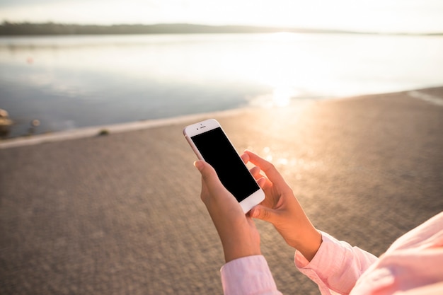 Free photo close-up of an woman using cellphone in front of lake