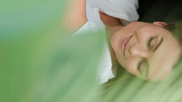 Free Photo close-up woman with closed eyes and blurred plant