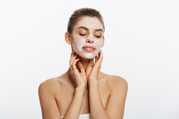 Close up of a woman with cosmetic facial mask applied over her face looking away