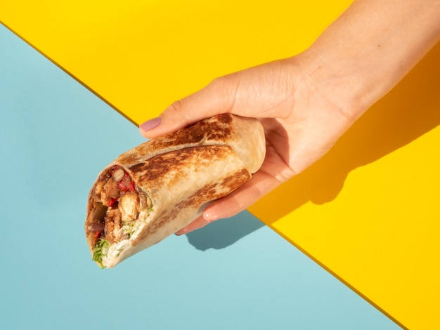 Close-up woman with delicious burrito and colorful background