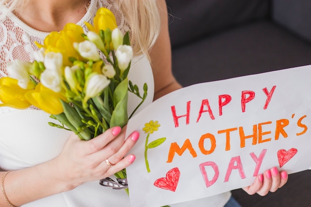 Free Photo close-up of woman with flowers and mother's day poster