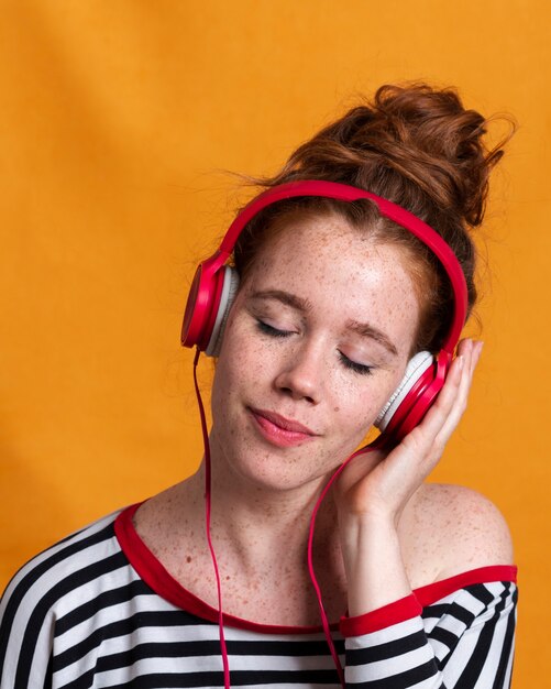 Close-up woman with headphones and orange background