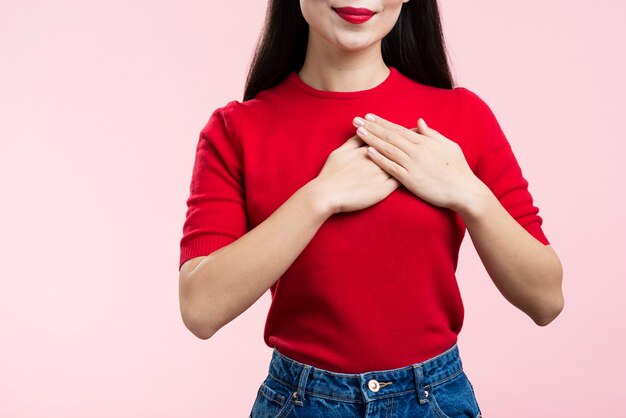 Close-up woman with red lips with hand on heart