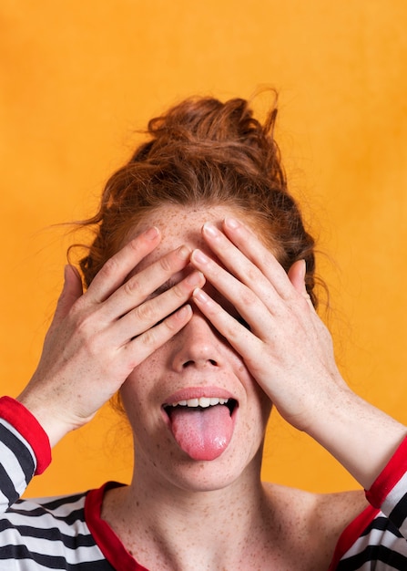 Free Photo close-up woman with tongue out covering her eyes