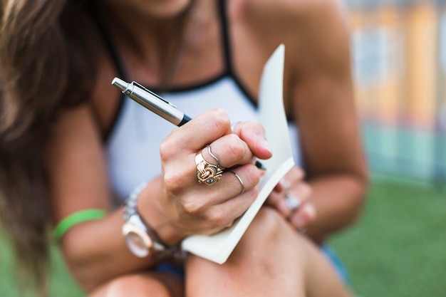 Close-up of woman writing on notebook with pen