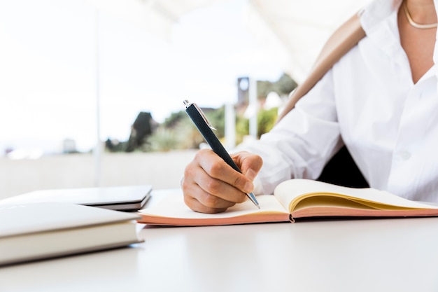 Close-up woman writing on notebook