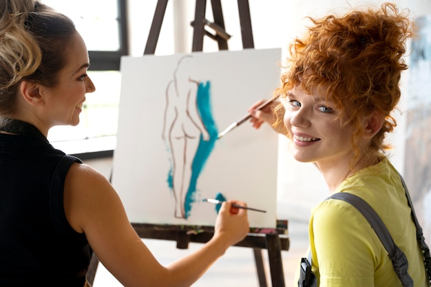 Free photo close up women painting on canvas together